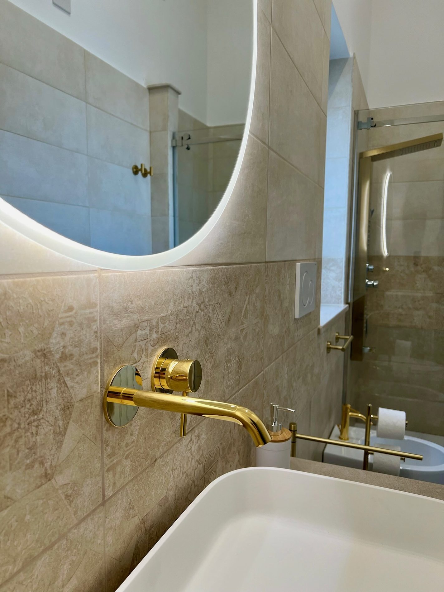 Bagno privato in pietra con rubinetteria dorata